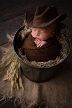 a newborn baby wearing a cowboy hat in a bucket