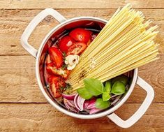 a pot filled with pasta and vegetables on top of a wooden table