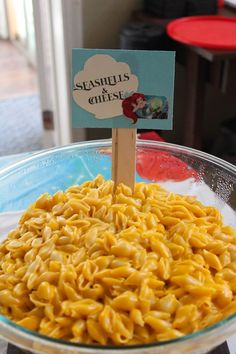 a glass bowl filled with macaroni and cheese sitting on top of a table