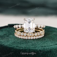 an emerald colored diamond ring set on top of a green velvet cushion