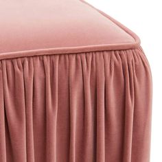 a pink bed skirt with pleating on the bottom and side, in front of a white background