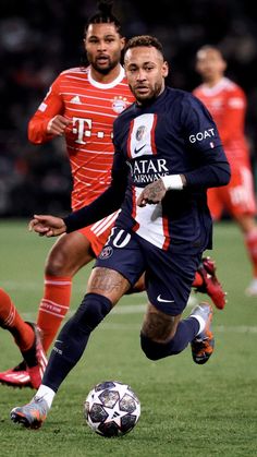 two men playing soccer on a field with one running after the ball while the other runs