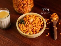 a wooden bowl filled with lots of food next to a glass of milk and spoon