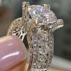 a close up of a person holding an engagement ring with diamonds on the sides and side