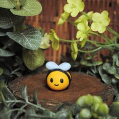 a small yellow and black bee sitting on top of a tree stump next to plants