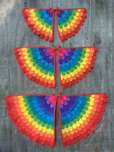 four kites made out of colored paper on a wooden table next to plants and a potted plant