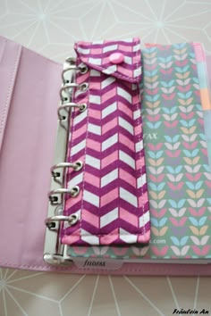 a pink binder with three different colored papers in it