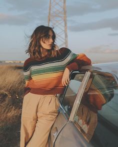 a woman leaning on the hood of a car