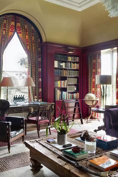 a living room filled with lots of furniture and bookshelves next to a window