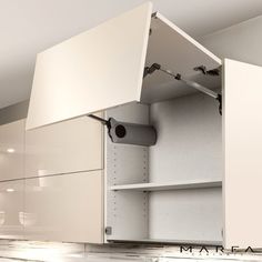 an open cabinet door in the middle of a kitchen with white cupboards and drawers