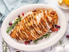 a white plate topped with sliced chicken and garnished with fresh cranberries