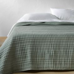 a bed with white pillows and green bedspread