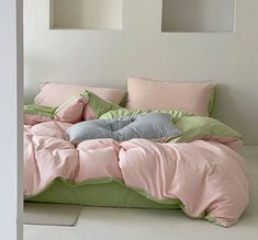 an unmade bed with pink and green comforters on the bottom, along with matching pillows