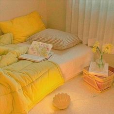 a bed with yellow sheets and pillows next to a basket full of flowers on the floor