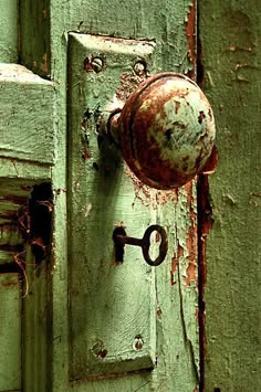 an old green door with a rusted knob and keyhole on the front handle