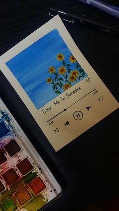 an artist's palette and watercolors are sitting on a table next to a notepad