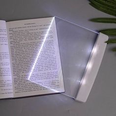 an open book sitting on top of a table next to a plant and some scissors