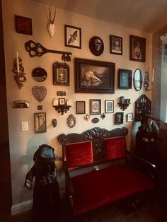 a living room filled with lots of framed pictures on the wall next to a red couch