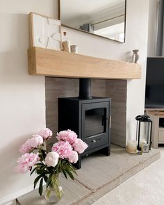 a vase filled with pink flowers sitting next to a fire place