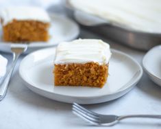 a piece of carrot cake on a plate with a fork and knife next to it