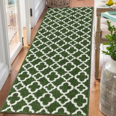 a green and white rug on the floor in front of a door with potted plants