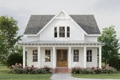 a white two story house with a porch and front door, surrounded by greenery