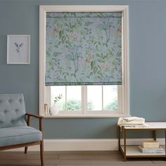 a living room with blue walls and a window covered in floral roman blind coverings