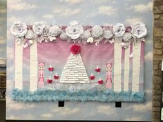 a wall hanging with paper flowers and decorations on it's side, in front of a brick wall