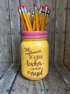 a yellow mason jar filled with pencils on top of a wooden table