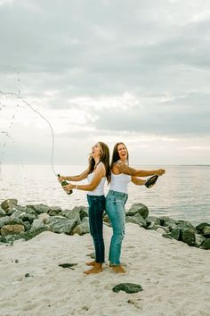 two women are on the beach playing with their wine bottles and kites in the air