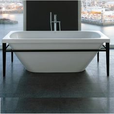 a white bath tub sitting on top of a tiled floor next to a large window