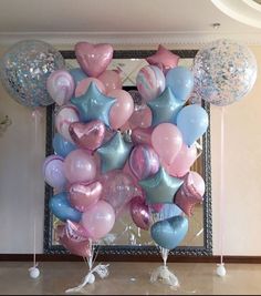 a bunch of balloons in the shape of hearts and stars are hanging from a wall