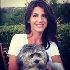 a woman sitting in a chair holding a dog