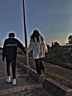 two people holding hands while walking down the street