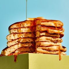 a stack of pancakes with syrup drizzled over them on top of a green box