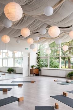 a large room with lots of yoga mats on the floor and lights hanging from the ceiling