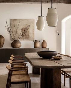 a dining room table surrounded by vases and chairs