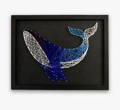 a blue and white whale string art in a black frame