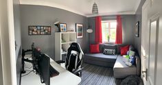 a living room with grey walls and red curtains on the window sill, gray couches, and black and white striped rugs