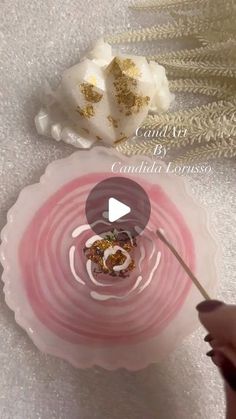 a person is holding a spoon in front of a pink bowl with gold flakes on it