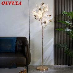 a floor lamp with flowers on it in a living room next to a black couch