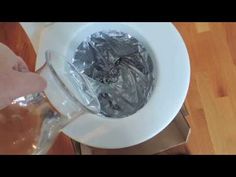 a person is pouring water into a toilet with tin foil on the seat and lid