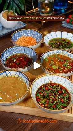 a wooden table topped with bowls filled with different types of soups and sauces