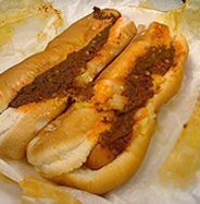 two chili cheese dogs in buns on wax paper