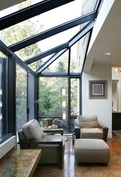 a living room filled with furniture under a skylight next to a large glass window