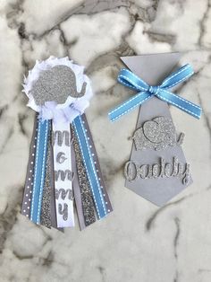 two silver and blue ribbons are next to an ornament on a marble surface