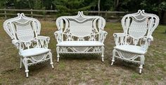 three white chairs sitting on top of a grass covered field