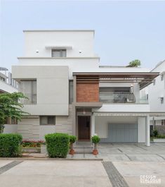 a modern house with white walls and brown shutters on the front, surrounded by greenery