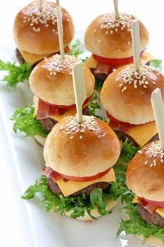 mini hamburgers with cheese and lettuce are arranged on a white platter