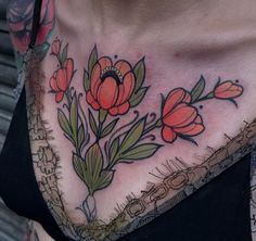 a close up of a woman's chest with tattoos on it and flowers in the middle